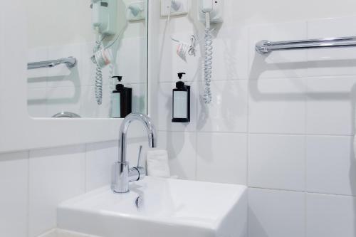 a white bathroom with a sink and a mirror at High Street Motel in Echuca