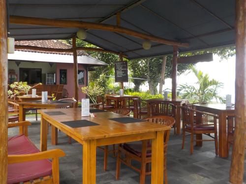 an outdoor restaurant with wooden tables and chairs at Reef Seen Divers' Resort in Pemuteran
