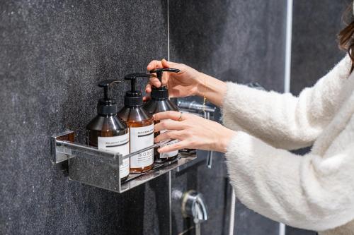 a woman is holding a soap dispenser in a shower at Guwol Rondo Hotel in Incheon