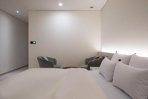 a bedroom with a white bed and two chairs at Guwol Rondo Hotel in Incheon