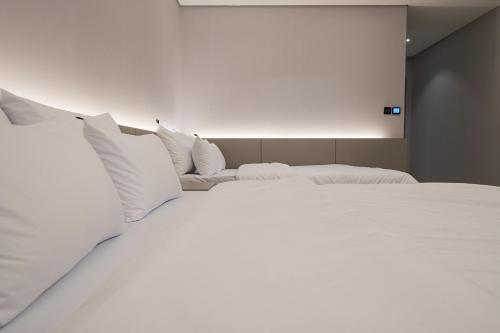 two beds in a room with white sheets and pillows at Guwol Rondo Hotel in Incheon