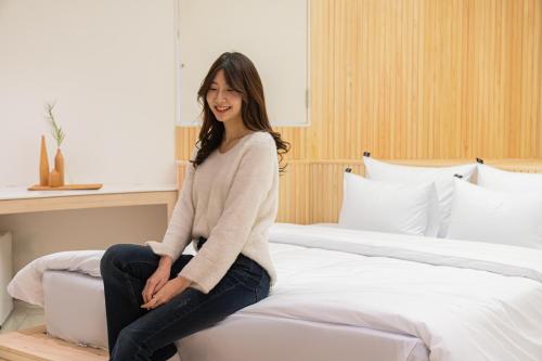 a woman sitting on top of a bed at Guwol Rondo Hotel in Incheon