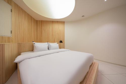 a large white bed in a room with a ceiling at Guwol Rondo Hotel in Incheon