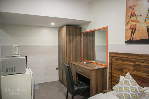 a room with a desk and a chair and a refrigerator at Byblos Hotel-Sky Osu in Accra