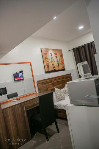 a bedroom with a desk and a bed with a computer at Byblos Hotel-Sky Osu in Accra