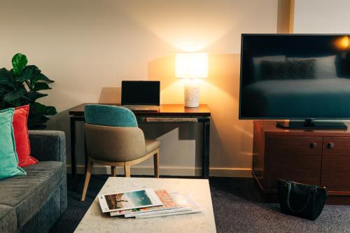 a living room with a couch and a desk with a television at Port Lincoln Hotel in Port Lincoln