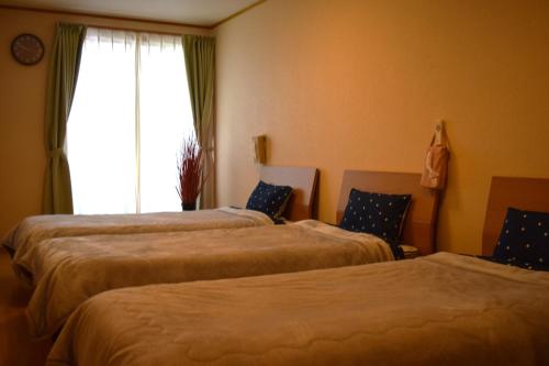 two beds in a room with a window at Hidamari in Takayama