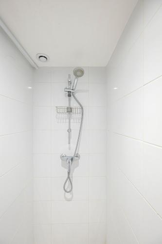 une douche dans une salle de bain avec du carrelage blanc dans l'établissement La Perle de Pau, à Pau