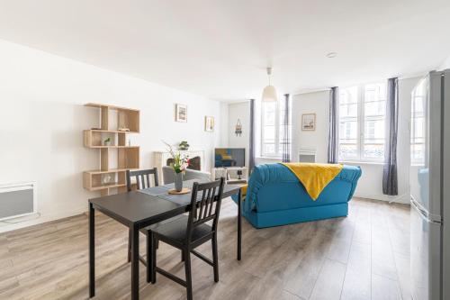 a living room with a table and a blue couch at La Perle de Pau in Pau