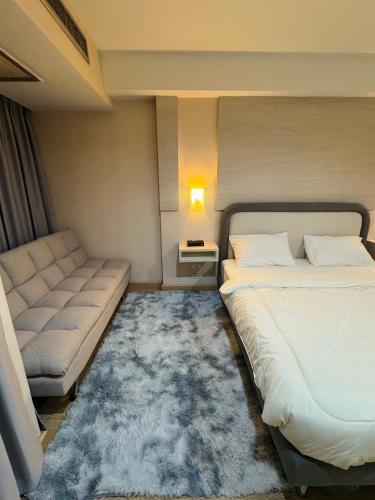 a bedroom with a bed and a couch and a rug at Inspire place rama9 Modern Condo near Rajamangala Stadium Pool and Gym in Bangkok