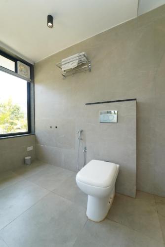 a bathroom with a white toilet and a window at Voyage Zo Lonavala in Lonavala