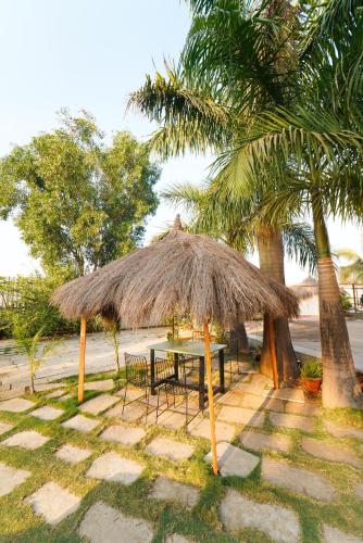 a table and chairs under a straw umbrella next to a palm tree at Voyage Zo Lonavala in Lonavala