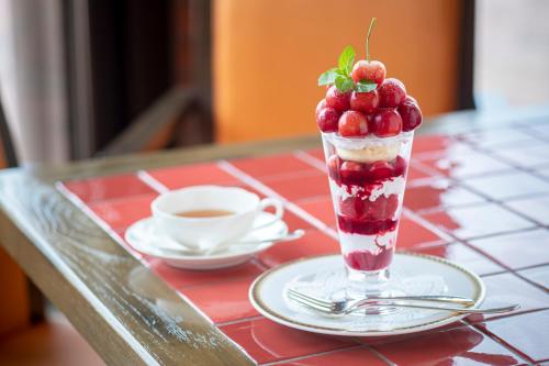 a dessert in a glass on a table with a cup of coffee at Fruit Park Fujiya Hotel in Yamanashi