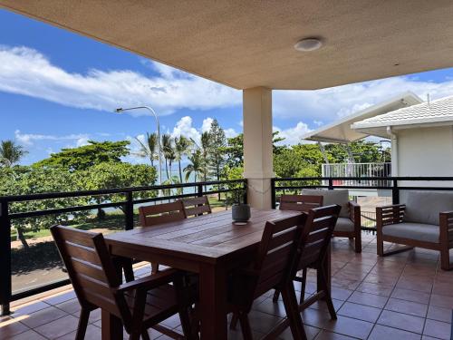 a wooden table and chairs on a balcony with a view at Townsville Apartments and Homes on The Strand in Townsville