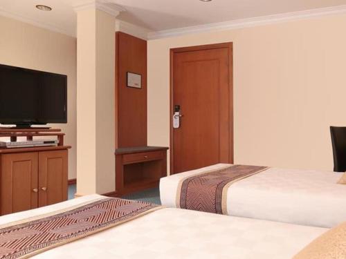 a hotel room with two beds and a flat screen tv at Hotel Sentosa in Kuala Belait