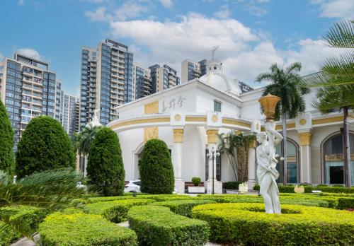 a white building with a statue in a garden at Castfast Hotel in Dongguan