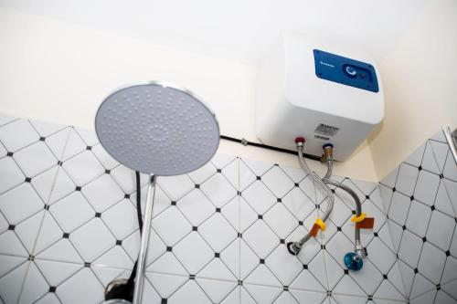 a white tiled bathroom with a shower with a shower head at Novella Guesthouse in Arua