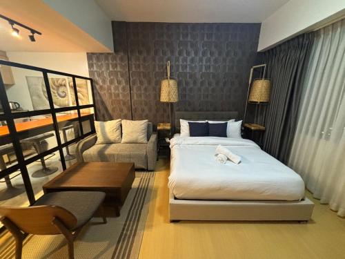 a bedroom with a bed and a couch and a chair at Cozy studio unit in Avant BG in Manila