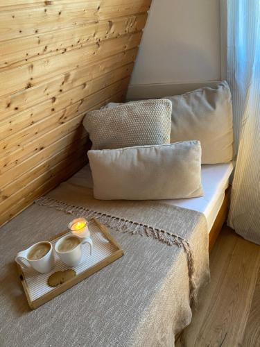 a bed with two cups and a tray with two candles at Ferienhaus am See im Fichtelgebirge in Nagel