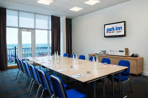 a conference room with a long table and blue chairs at Park Inn by Radisson Palace in Southend-on-Sea