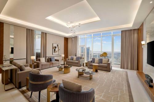 a living room with couches and chairs and a large window at Hilton Bahrain City Centre Hotel & Residences in Manama