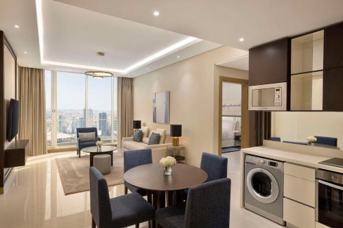 a living room with a kitchen and a living room with a table at Hilton Bahrain City Centre Hotel & Residences in Manama
