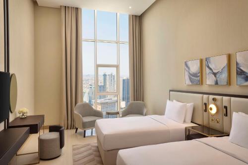 a hotel room with two beds and a window at Hilton Bahrain City Centre Hotel & Residences in Manama