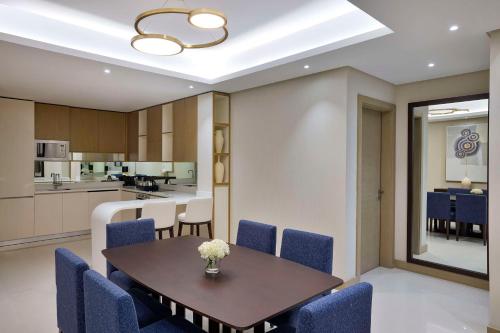 a kitchen and dining room with a table and blue chairs at Hilton Bahrain City Centre Hotel & Residences in Manama