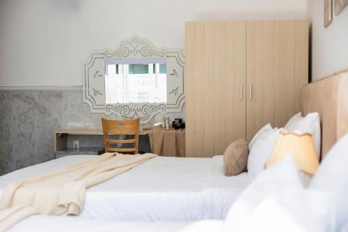a bedroom with two white beds and a desk at Nghia Lan Hotel in Da Lat