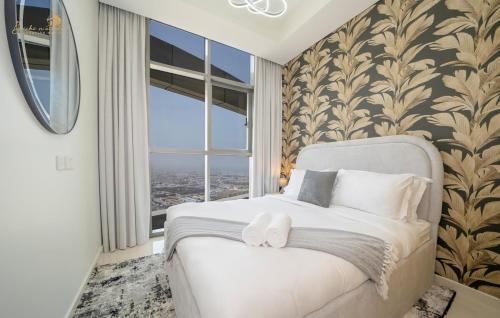 Un dormitorio con una cama blanca con una ventana grande. en Modern Sunset View 2Bhk 6pax, en Dubái