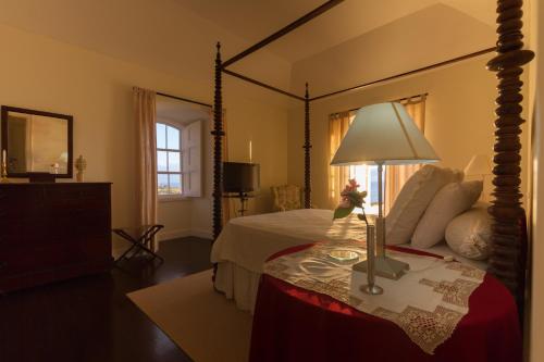 a bedroom with a large canopy bed with a table with a lamp at Casa da Rocha Quebrada in Lagoa