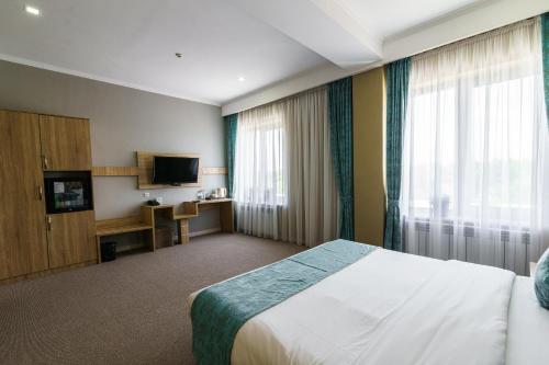 a hotel room with a bed and a television at Park Hotel al Bustan in Shymkent