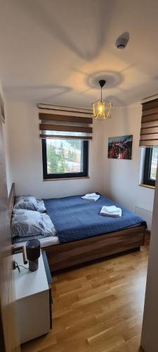 Un dormitorio con una cama con sábanas azules y una ventana. en Stars Apartman Jahorina, en Jahorina