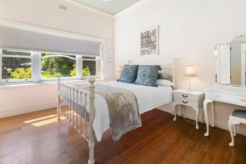 een witte slaapkamer met een bed en een ladekast bij Coral Rose Cottage in Capel Sound