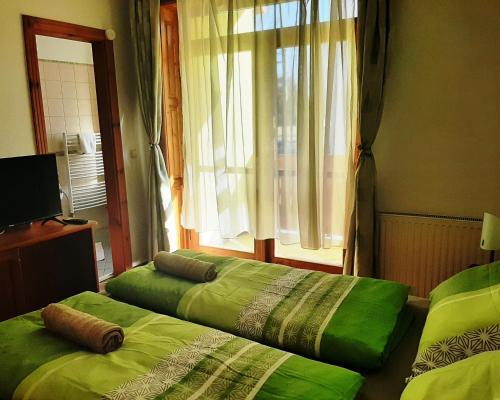 two beds sitting in a room with a window at Szt Kristóf Bed and Breakfast in Győr