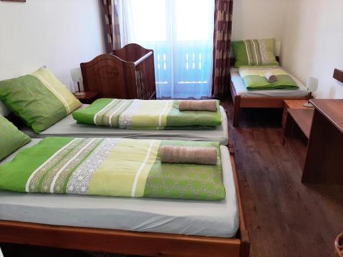 three beds in a room with green and yellow blankets at Szt Kristóf Bed and Breakfast in Győr