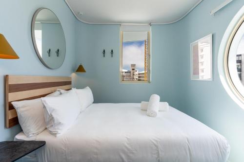 a bedroom with a white bed and a mirror at The Tropicana Hotel in Cape Town