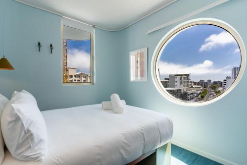 a bedroom with a white bed and a round window at The Tropicana Hotel in Cape Town