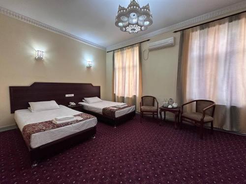 a hotel room with two beds and a chandelier at Grand Silk Road in Samarkand