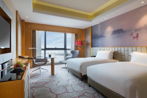 a hotel room with two beds and a desk at Pullman Wenzhou in Wenzhou