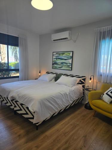a bedroom with a large bed and a yellow chair at לוי-קיישן מגוון דירות גן ופנטהאוזים וסוויטות נוף ברחוב הצנחנים in Tiberias