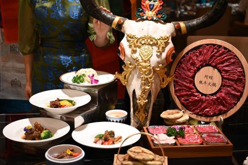 a table topped with plates of food next to a woman at Pullman Wenzhou in Wenzhou