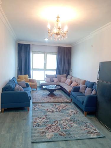 a living room with blue couches and a chandelier at شقه على النيل in Luxor