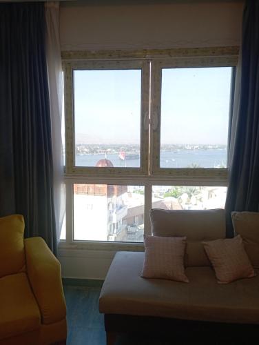 a living room with a couch and a large window at شقه على النيل in Luxor