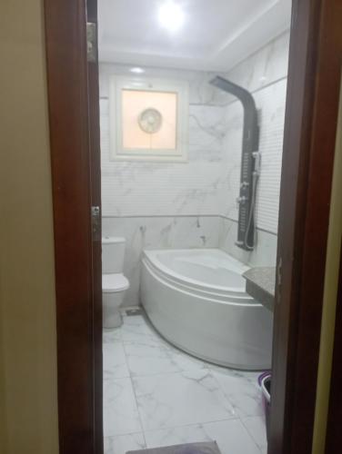 a bathroom with a tub and a toilet and a sink at شقه على النيل in Luxor
