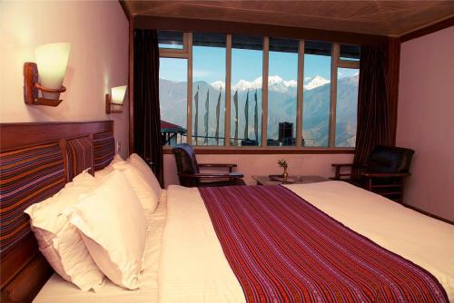 a bedroom with a bed with a view of mountains at Hotel Sikkim Tourist Centre in Pelling