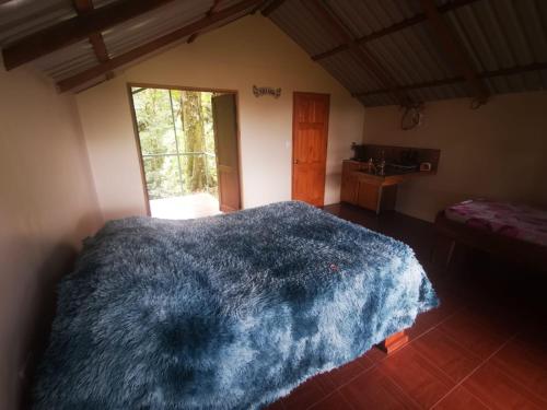 Un dormitorio con una manta azul en una cama en Cabaña Mono Cariblanco, en Aguas Zarcas