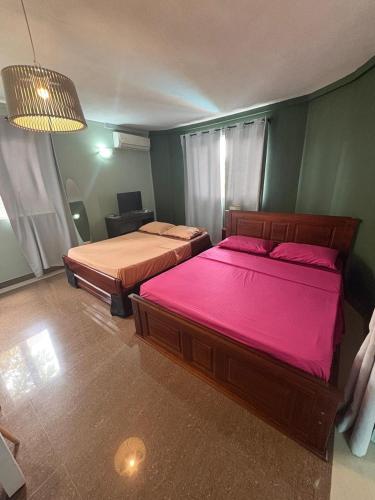 a bedroom with two beds with pink sheets at Lariad BNB in Rivière Noire