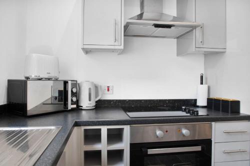 a kitchen with white cabinets and a black counter top at WhiskAwayStays Foregate Studio No 2 in Worcester