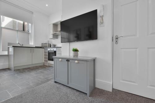 a kitchen with white cabinets and a flat screen tv at WhiskAwayStays Foregate Studio No 2 in Worcester